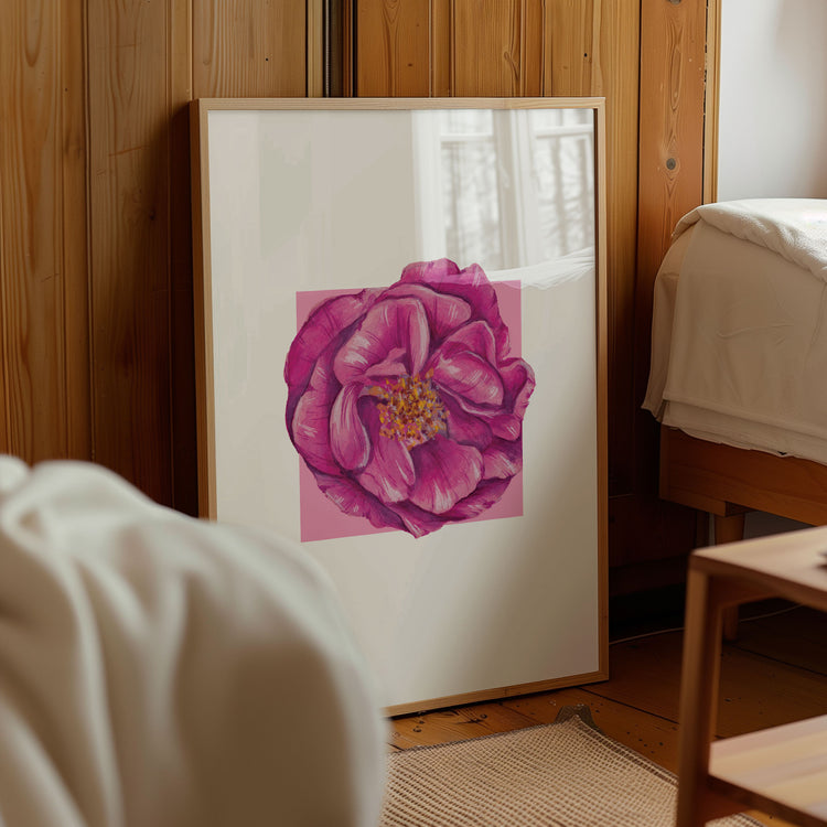 Framed artwork of a pink rose flower on a wall in a room with wooden paneling.