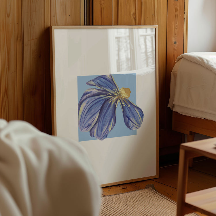Framed artwork of a blue dune flower on a wall in a room with wooden paneling.
