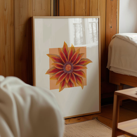 Framed artwork of a Gazania flower on a wall in a room with wooden paneling.