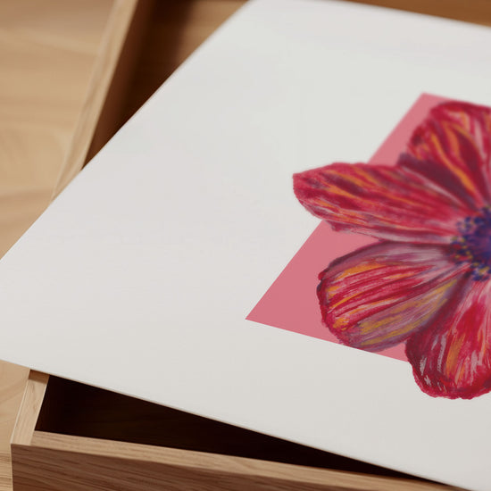 Close-up of red flower illustration on a white card with a wooden box in the background