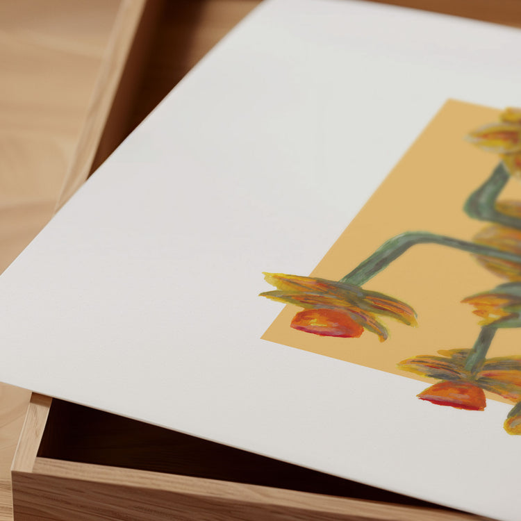 Close-up of a framed artwork with a yellow floral design on a wooden surface