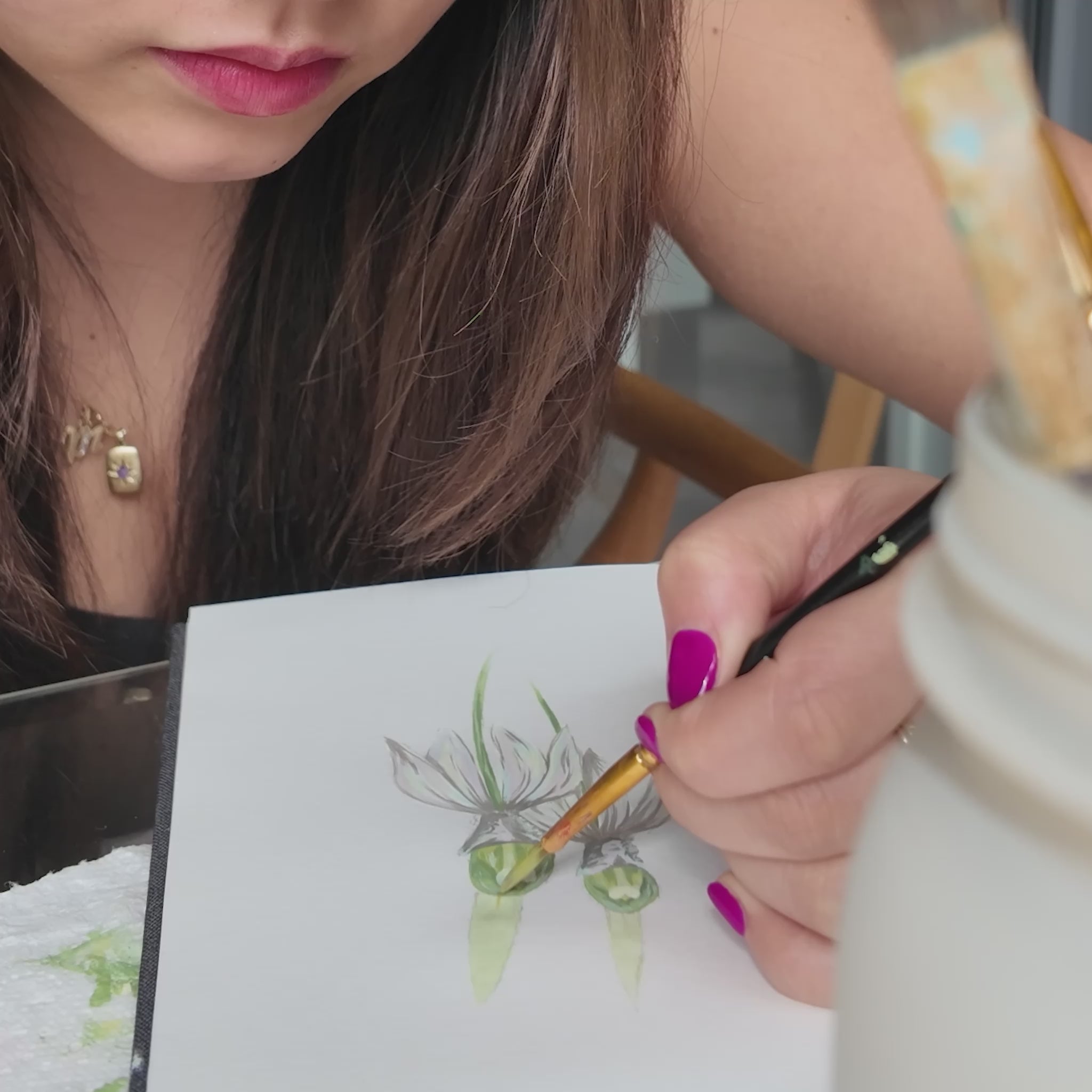 Girl holding a paint brush painting a white orchid flower